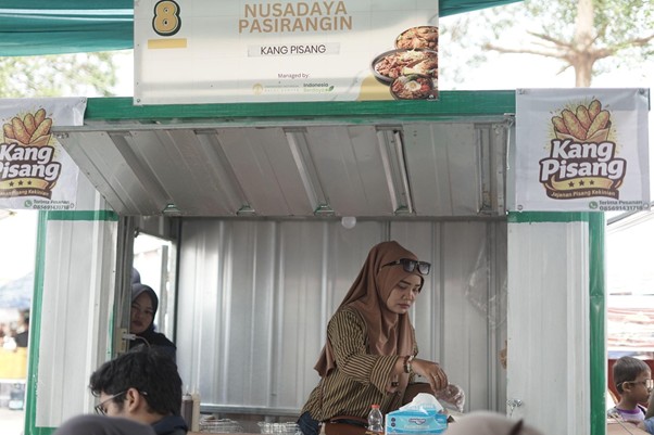 foodcourt nusadaya bogor 10 dompet dhuafa Woman in a brown hijab serves pastries at a Kang Pisang street stall.
