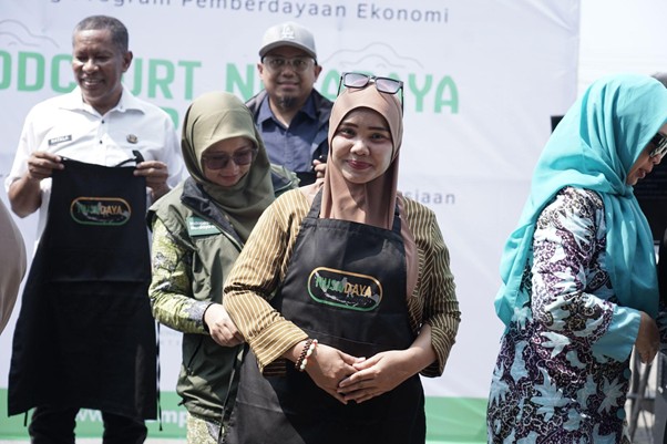 foodcourt nusadaya bogor 5 dompet dhuafa Group of people at a community event wearing black aprons with a logo, standing in front of a banner.