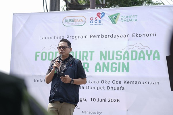 foodcourt nusadaya bogor 6 dompet dhuafa Male speaker with a microphone on a stage during an economic empowerment program launch, banners and logos visible in the background.