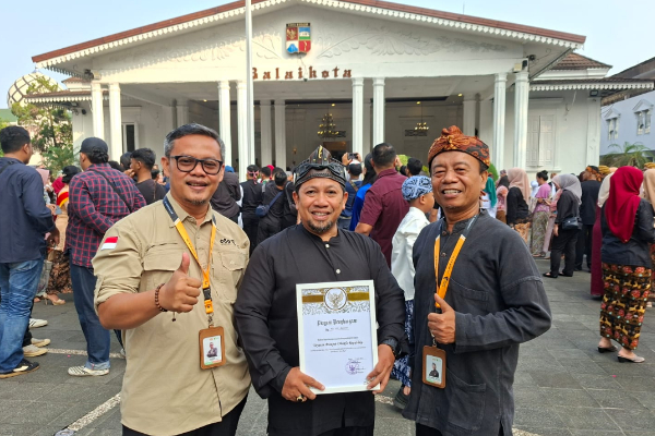 fotojet 1 dompet dhuafa Three men pose for a photo in front of a white, columned building with a crowd; the center man holds a certificate while the others show thumbs up.