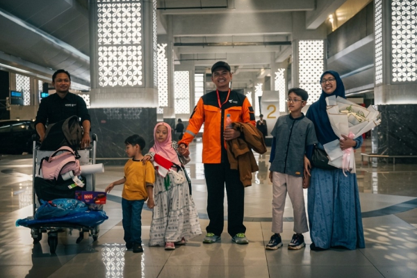 fotojet 4 dompet dhuafa Family of six with luggage stands together in a bright airport terminal.