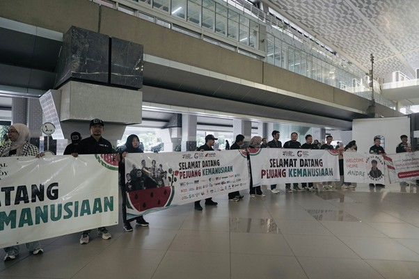 kedatangandelegasigsf203 1 dompet dhuafa Group of people standing in a modern airport-style concourse, holding large banners with Indonesian text about humanitarian efforts.