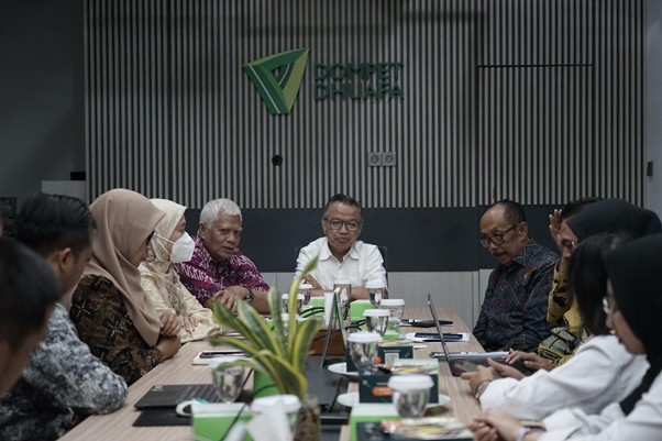 Group of diverse professionals seated around a conference table in a modern office, discussing a meeting.