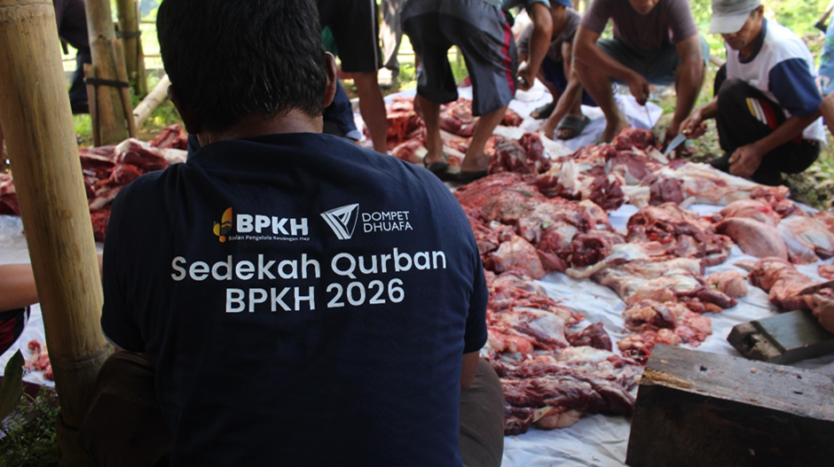 kurban bpkh 2 dompet dhuafa Volunteer wearing a dark shirt with 'Sedekah Qurban BPKH 2026' logo, seated among heaps of meat prepared for distribution.