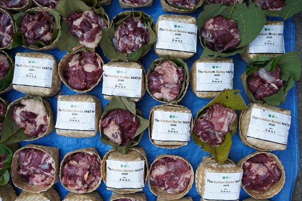 Rows of small woven baskets filled with raw meat pieces on a blue tarp, each with a white label reading 'The Kurban Series'