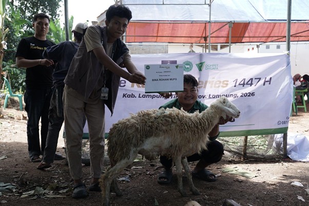 kurban di lampung timur 2 dompet dhuafa Group of men at an outdoor livestock event presenting a sheep and a certificate in front of a banner.