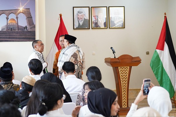peringatanharinakbake782 dompet dhuafa Officials in traditional attire greet attendees at a formal ceremony with a lectern and flags nearby.