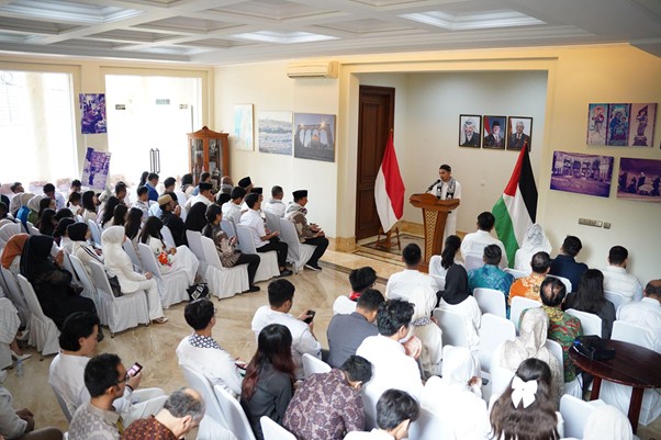 peringatanharinakbake787 dompet dhuafa Speaker at a podium addressing a large audience in a bright hall, with Indonesian and Palestinian flags on stage.