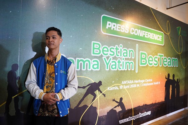 Young man in a blue-and-white jacket stands before a colorful banner that reads 'Press Conference' and 'Bestian Rama Yatim | BestTeam,' with silhouetted figures and event details in the background.