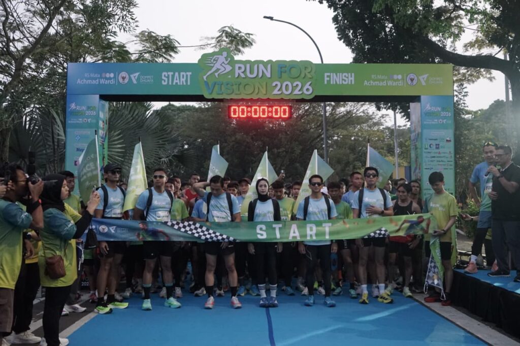 Group of runners lined up at the start banner of a race, 'RUN FOR VISION 2026' with a digital timer showing 00:00:00 and a large START banner above.