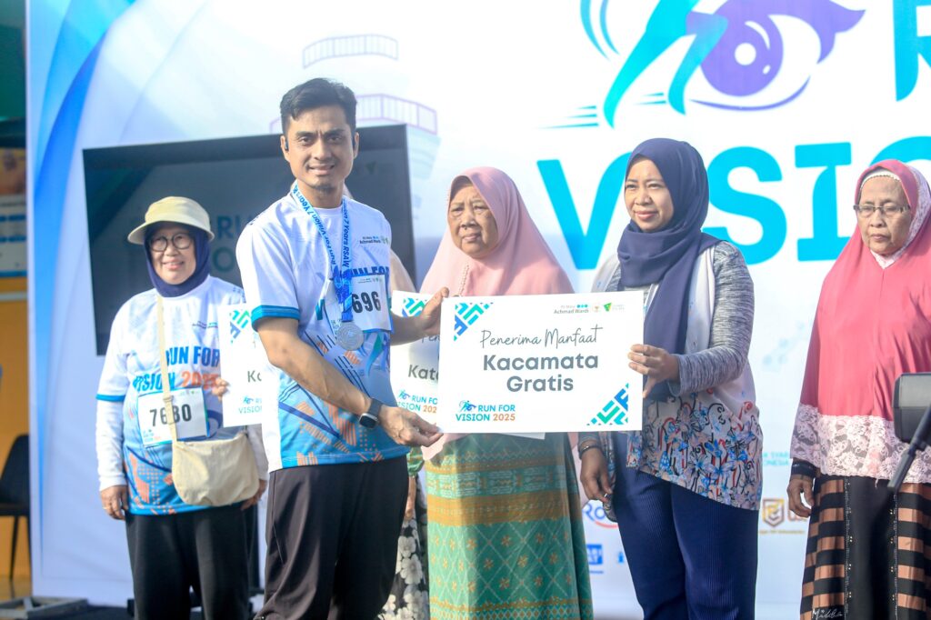 run for vision 2026 1 dompet dhuafa Group of diverse adults at an awards ceremony exchanging a certificate for free glasses, with a bright event backdrop behind them.