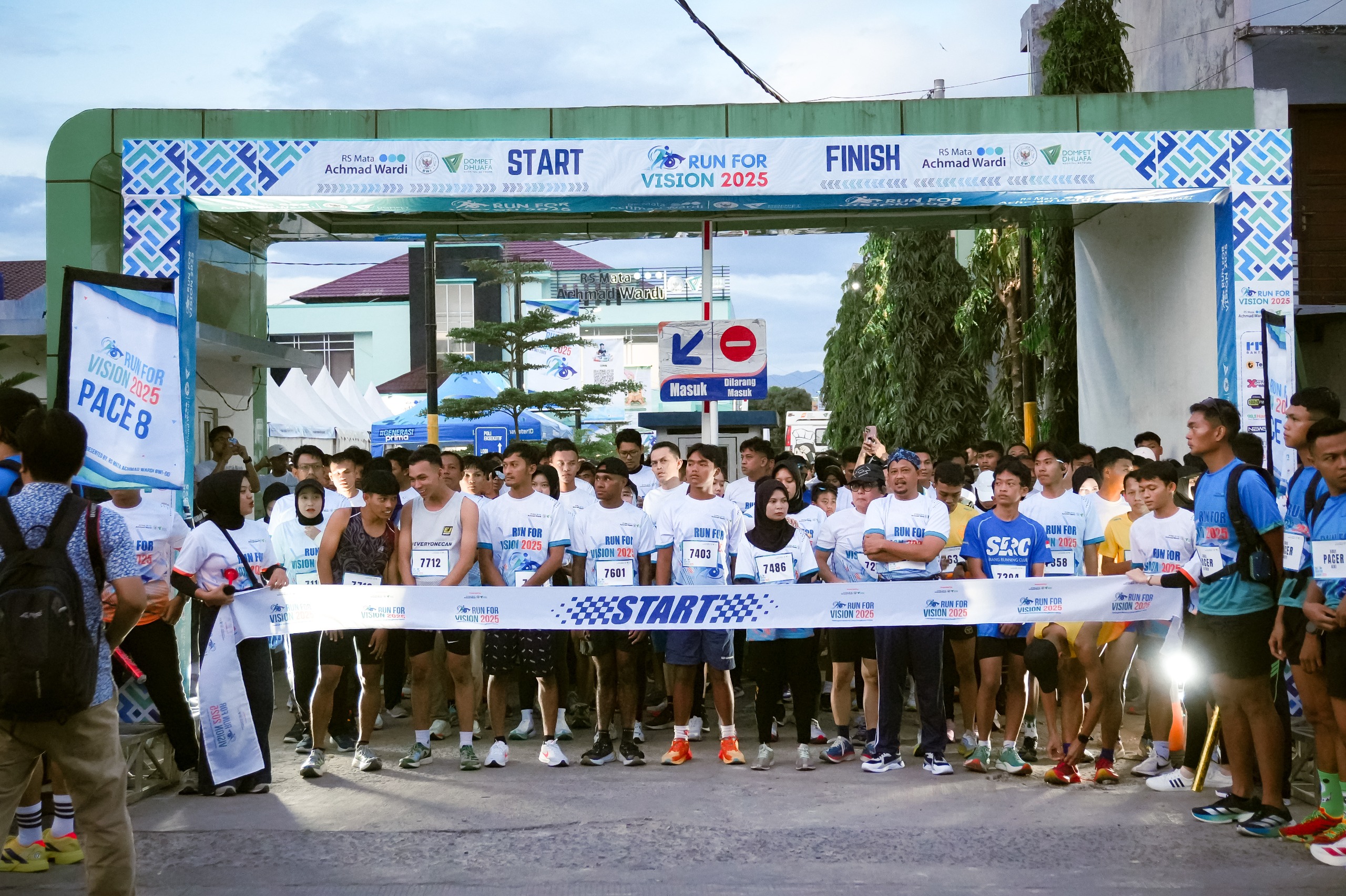 run for vision 2026 6 dompet dhuafa Group of runners at the starting line of a race, wearing white shirts and bib numbers under a START banner.