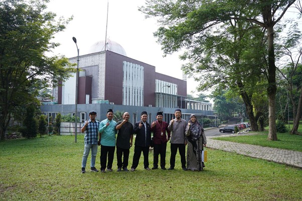 sensei sugimoto kunjungi smart 1 dompet dhuafa Eight people standing in a row on a grassy lawn, giving thumbs up in front of a modern building with a domed roof and trees nearby.
