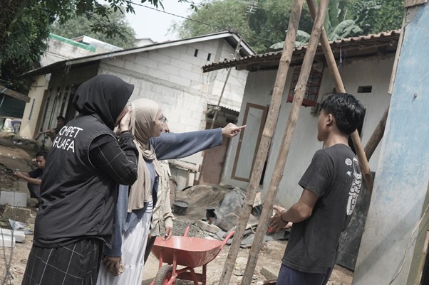 zakatptadev2 dompet dhuafa Two women wearing headscarves talk to a young man at a construction site; one woman points toward a doorway while others watch.
