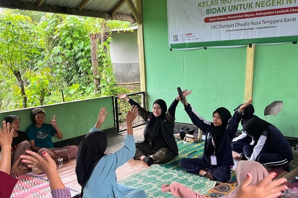 penghargaan untuk bidan untuk negeri 2 dompet dhuafa Women wearing hijabs sit in a circle on colorful mats under a shelter, raising hands during a community class; a green wall and banner indicate a local program.
