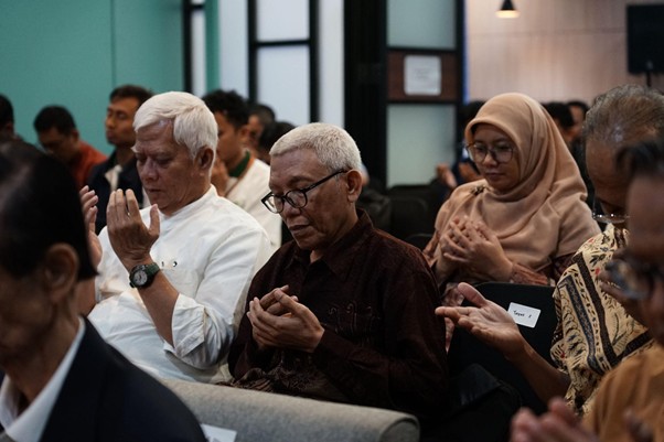 refleksijatidiri15 dompet dhuafa Diverse group seated in a conference room, with hands cupped in a prayerful gesture.