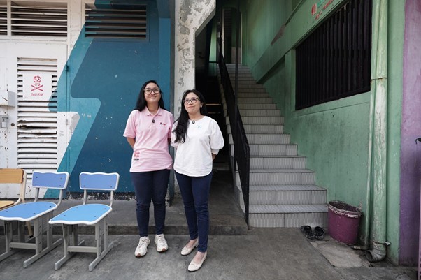 ruang praktikum di smk mitra permata 11 dompet dhuafa Two students stand side by side outside a colorful building with a blue stairwell and mural.