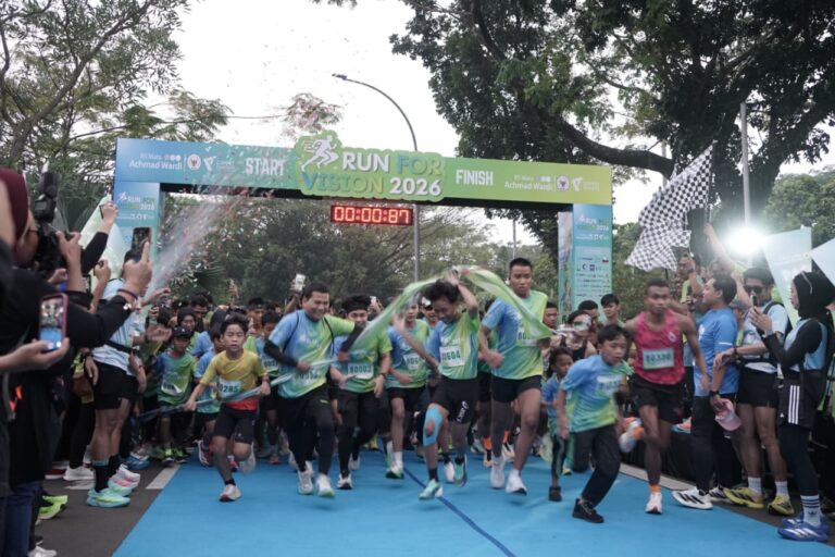 runforvision2768x512 dompet dhuafa Runners sprint from the starting line under a green banner reading 'Run for Vision 2026' while cheering spectators line the sides.